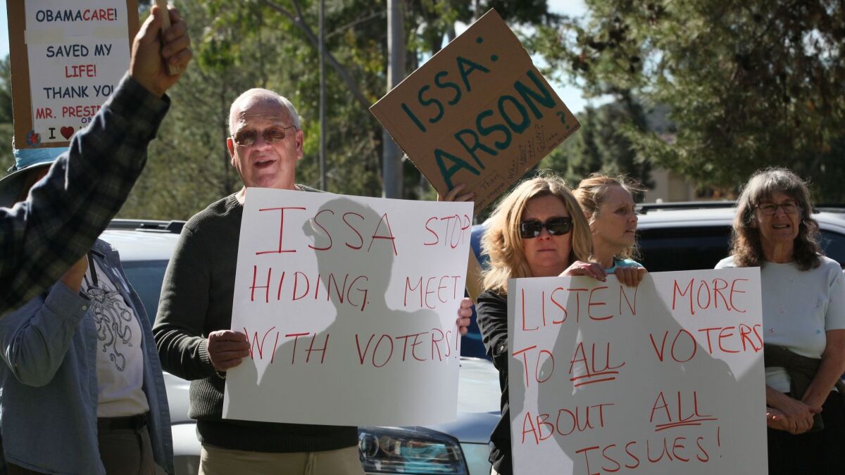 Retired U.S. Marine Tim O'Healy, left, with his wife, Misty O'Healy, joined more than 100 people gathered last Tuesday outside of Rep. Darrell Issa's Vista office. (Peggy Peattie / San Diego Union-Tribune)