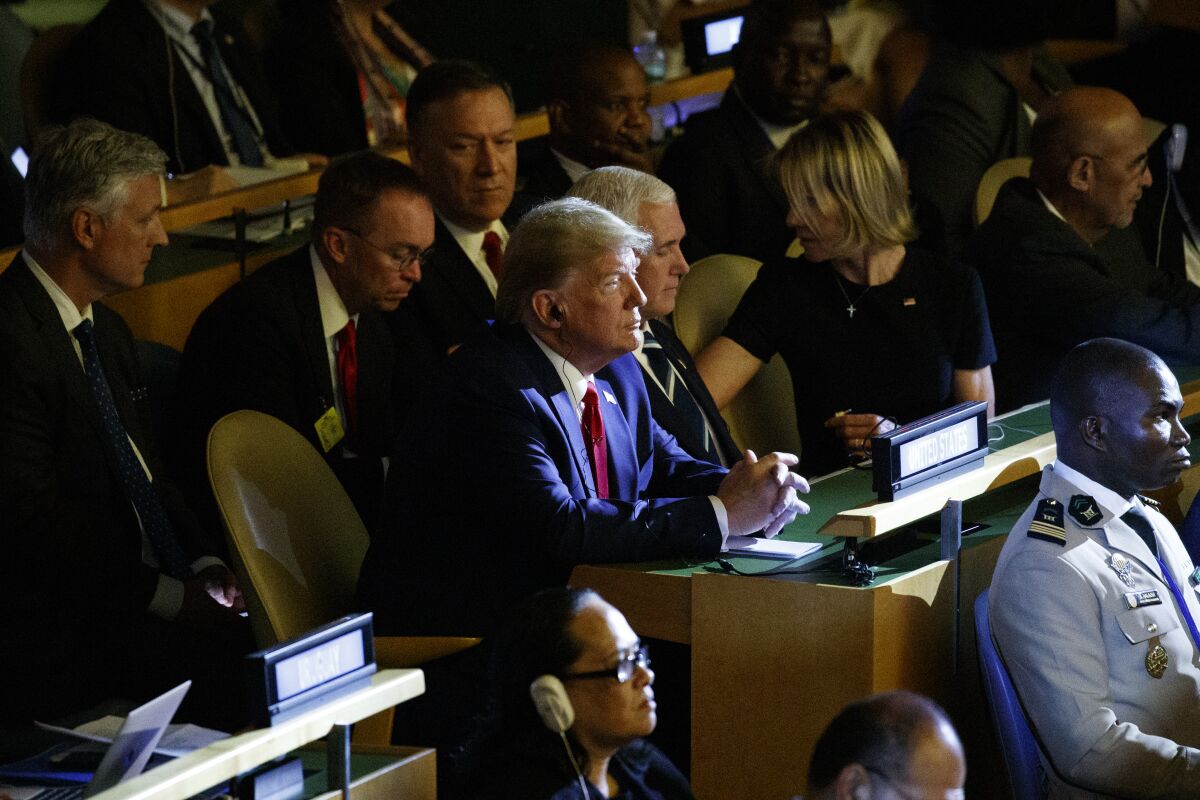 Donald Trump sits at a desk.