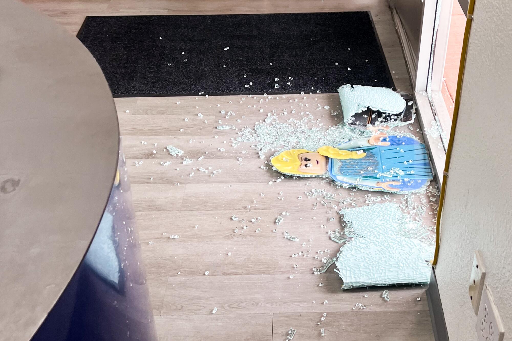 A cutout of a Lego figurine is surrounded by broken glass on the floor of Bricks & Minifigs in Whittier