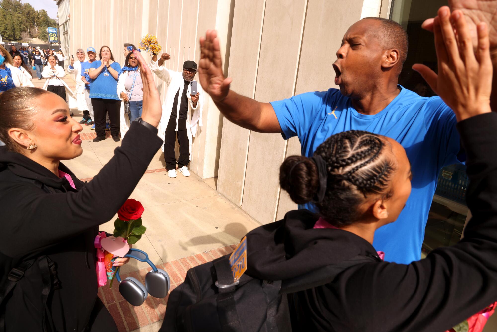 UCLA'nın süper hayranı Michael Reese (sağda), uğurlama töreninde Bruins jimnastik takımının üyelerine beşlik çakıyor.