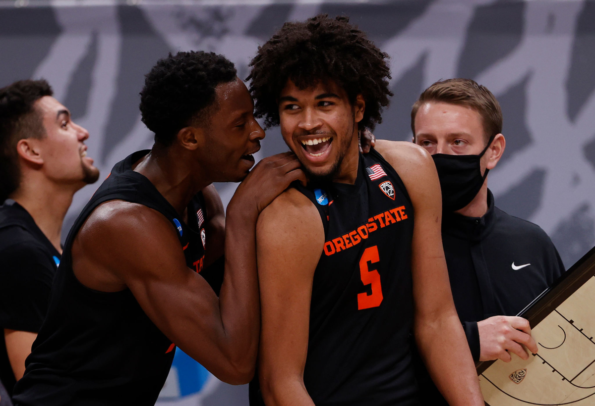 Ethan Thompson smiles while standing with others on the sideline.