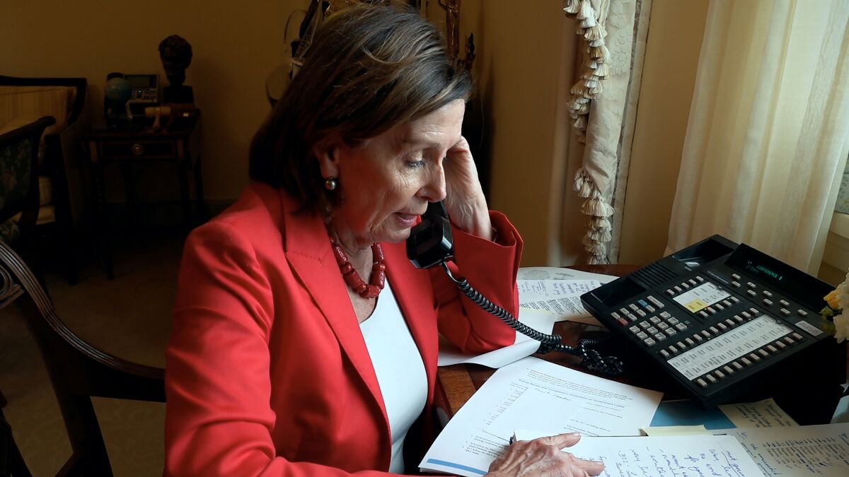 A woman in a red suit jacket speaks on a telephone in "Pelosi in the House."