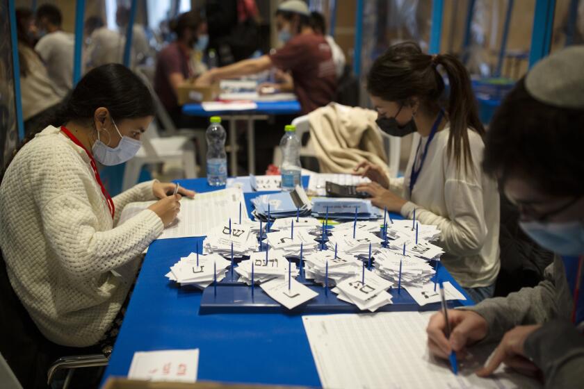 Workers count votes in Israel's national elections wearing and divided in groups by sheets of plastic masks to help curb the spread of the coronavirus, at the Knesset in Jerusalem, Thursday, March 25, 2021. (AP Photo/Maya Alleruzzo)