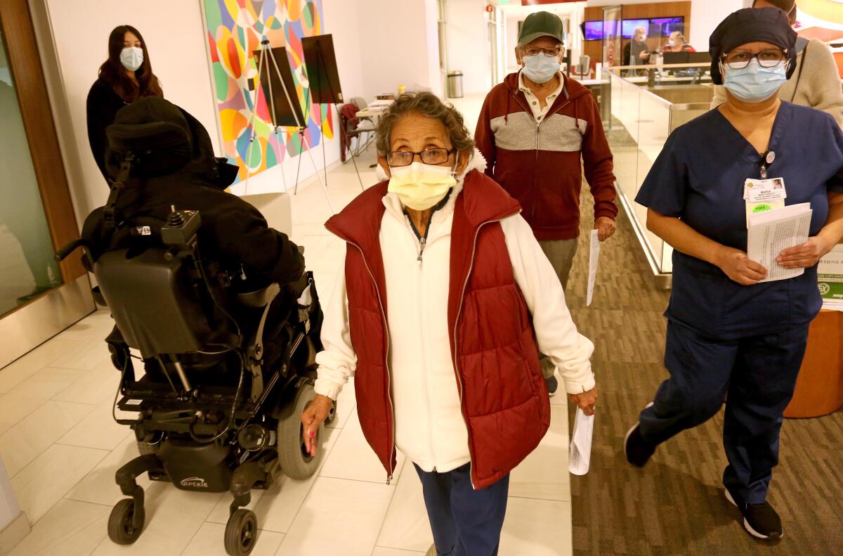 People walk down a hospital corridor 