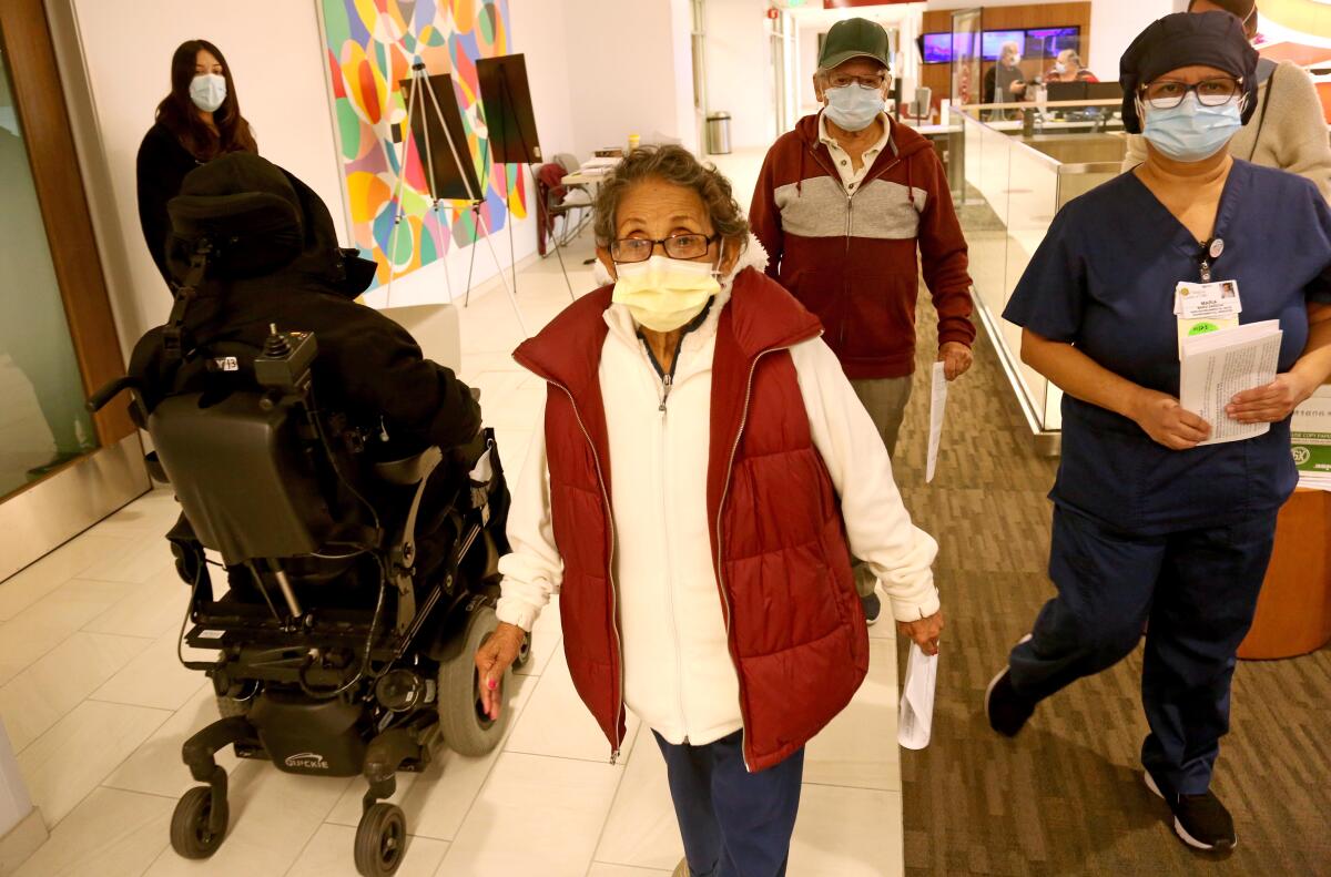 People walk down a hospital corridor