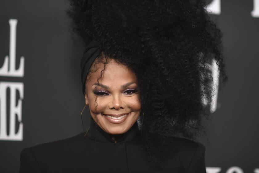 Janet Jackson smiles in a black turtleneck.