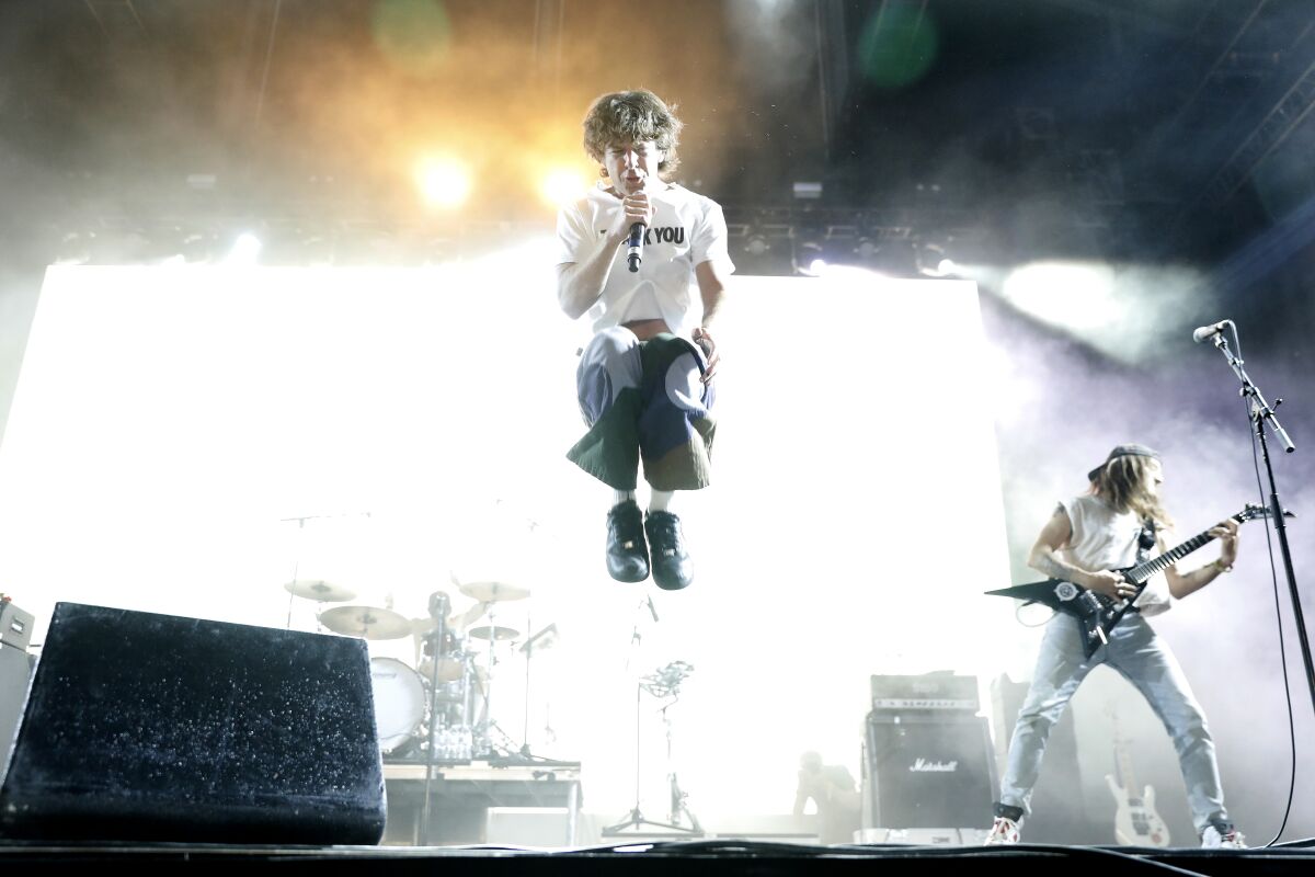 A male singer jumps into the air during his band's performance