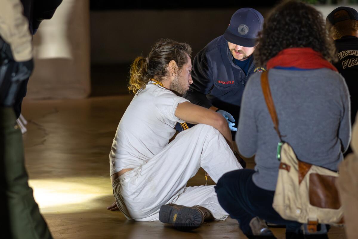 Paramedics tend to Cyrus Mayer, who was dragged out of an Ojai City Council meeting after a "die-in" protest.