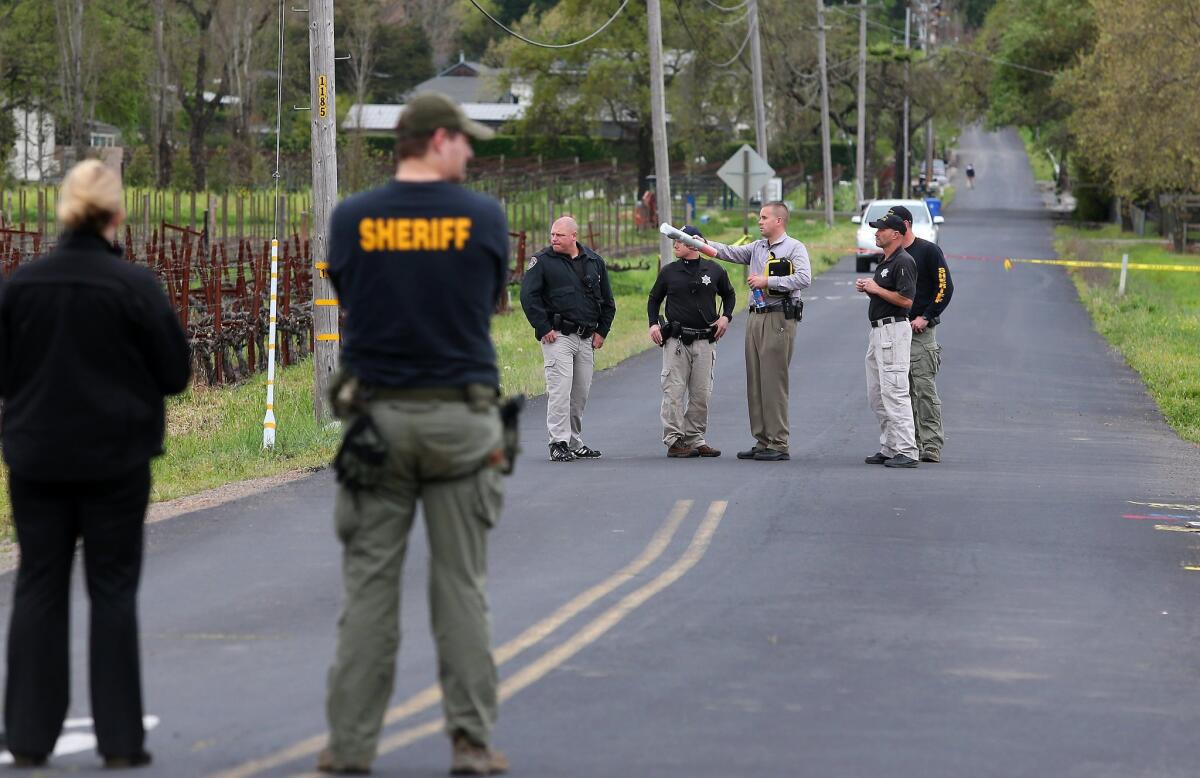Law enforcement officials stand outside a vineyard where two men were found shot to death, part of a deadly string of incidents in the Northern California city.