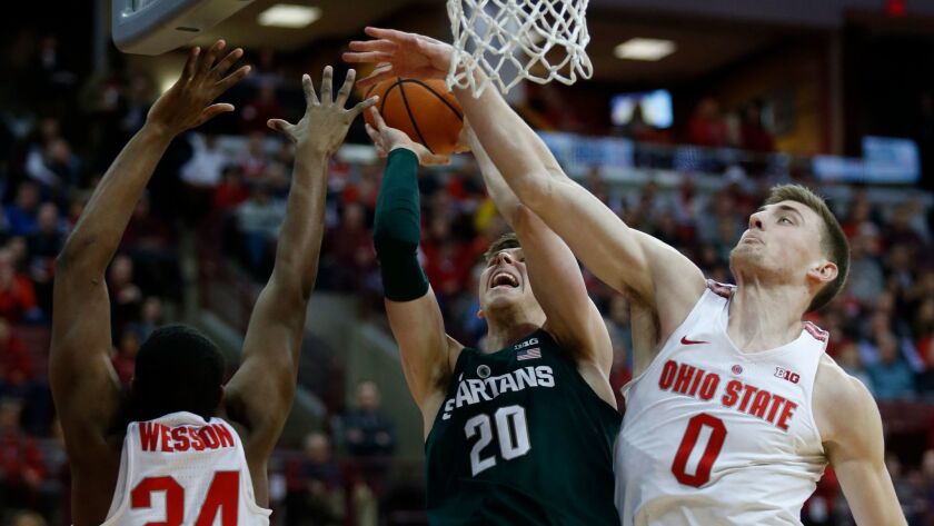 Michigan State guard Matt McQuaid goes up to shoot between Ohio State forward Andre Wesson and center Micah Potter during the first half.