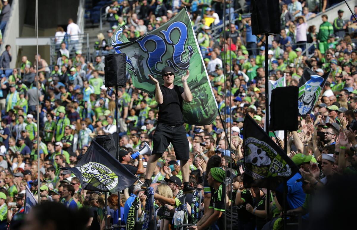 A "capo" with the Emerald City Supporters stands on the top rails of the stand he uses to lead cheers and songs during the second half of an MLS soccer match between the Seattle Sounders and the Portland Timbers, Sunday, Aug. 30, 2015, in Seattle. (AP Photo/Ted S. Warren)