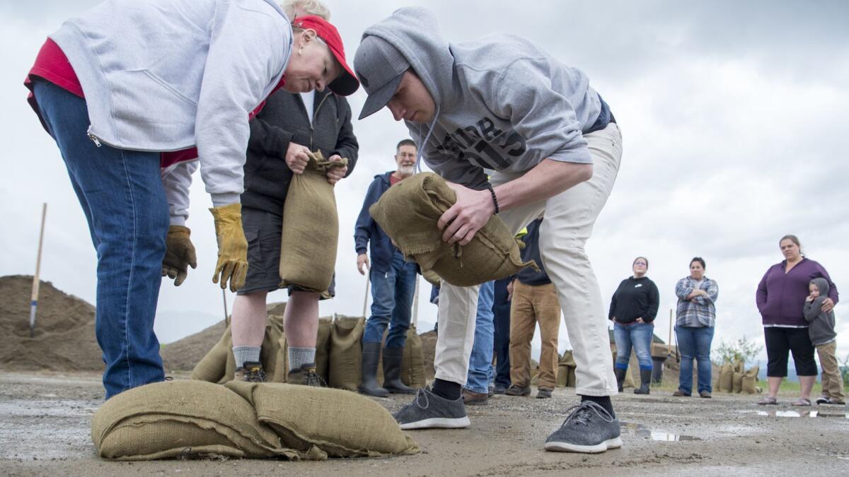 Ryan Revard, center, learns how to place sandbags to build a dike at the Kalispel Tribe headquarters in Usk, Wash., as part of a class Wednesday. Washington state Gov. Jay Inslee proclaimed a state of emergency Saturday for flooded counties in the region.