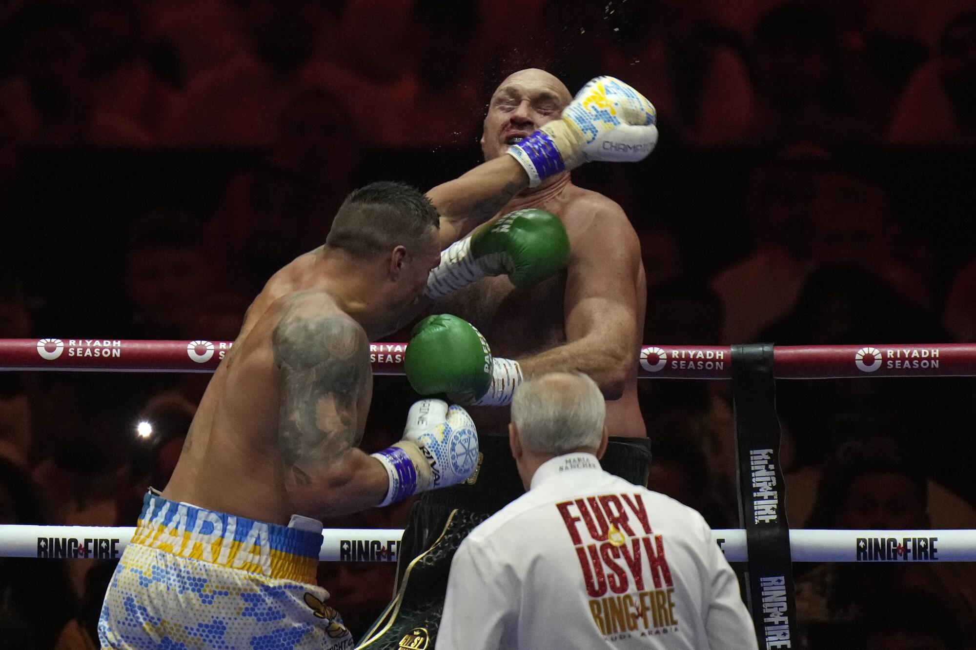 Britain's Tyson Fury, rear, takes a blow from Ukraine's Oleksandr Usyk.