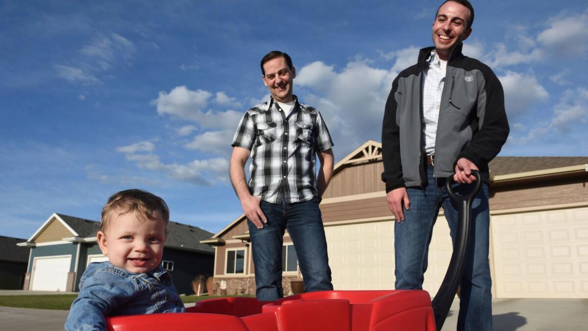 Greg Roling, center, and Larry Sandal take a stroll with their 9-month-old adopted daughter, Emmersyn Julia Roling, in Sioux Falls, S.D., in April 2017. (Jay Pickthorn / Associated Press)