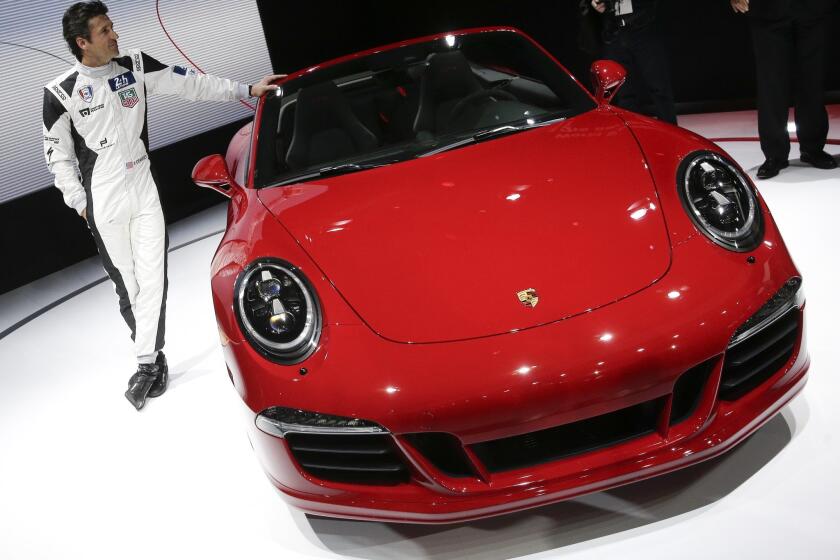 Actor Patrick Dempsey poses next to the 2015 Porsche 911 Carrera GTS during the Los Angeles Auto Show on Wednesday. Porsche North America said that Dempsey will race in the 24 Hours of Le Mans in 2015 in a Porsche 911 RSR.