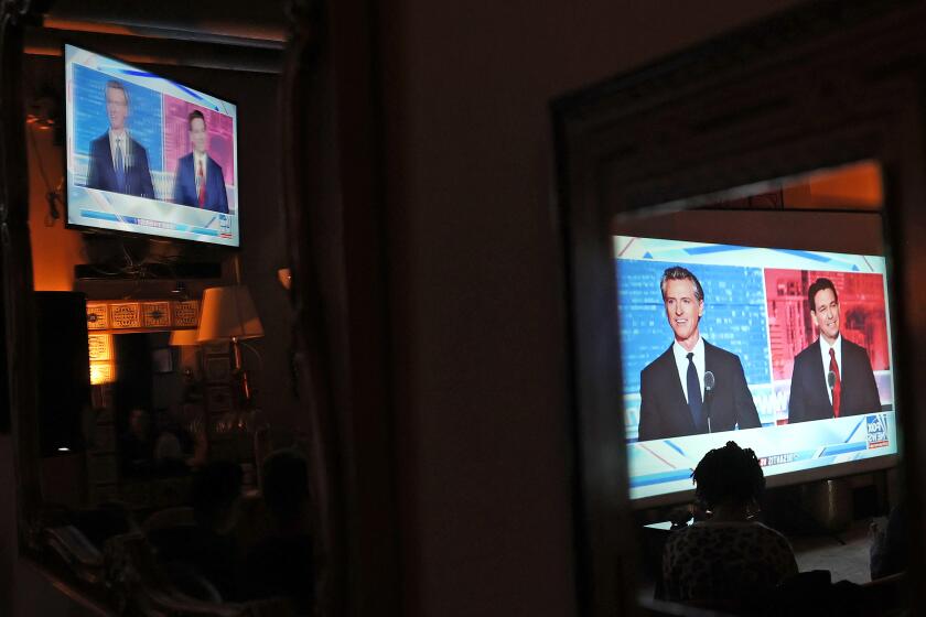 SAN FRANCISCO, CALIFORNIA - NOVEMBER 30: California Gov. Gavin Newsom and Florida Gov. Ron DeSantis are seen reflected in a mirror during a watch party at Manny's on November 30, 2023 in San Francisco, California. Newsom and DeSantis were hosted by Sean Hannity on Fox. (Photo by Justin Sullivan/Getty Images)