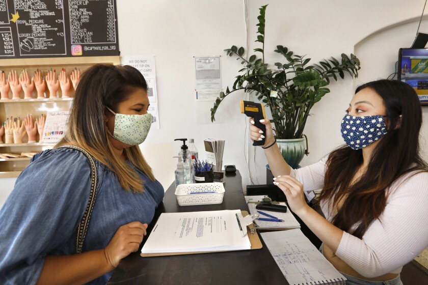 Melissa Alatorre, left, gets her temperature before getting her nails done at Captivate Nail & Spa in Fullerton.