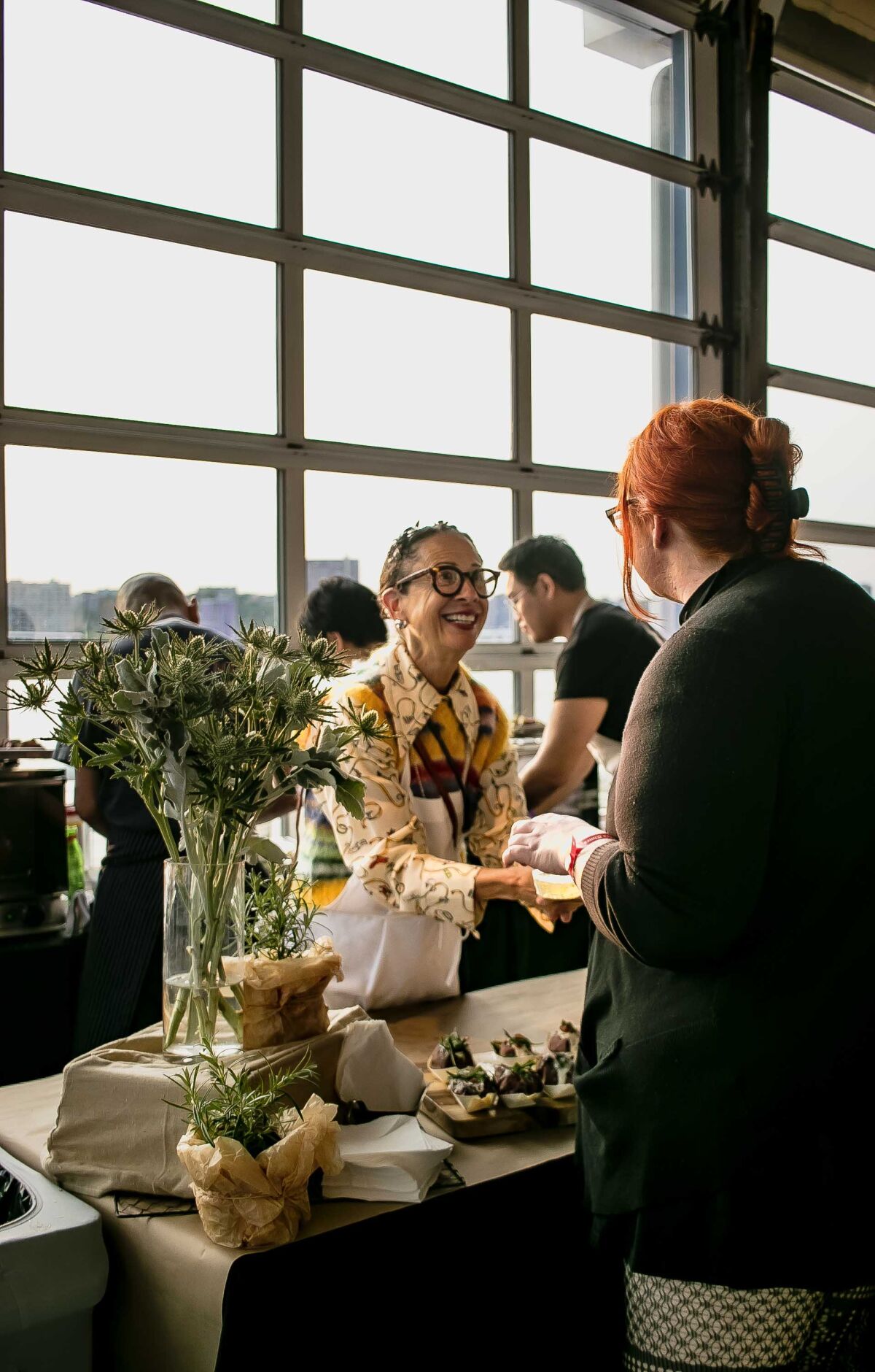 A chef hands a plate to a person facing her.