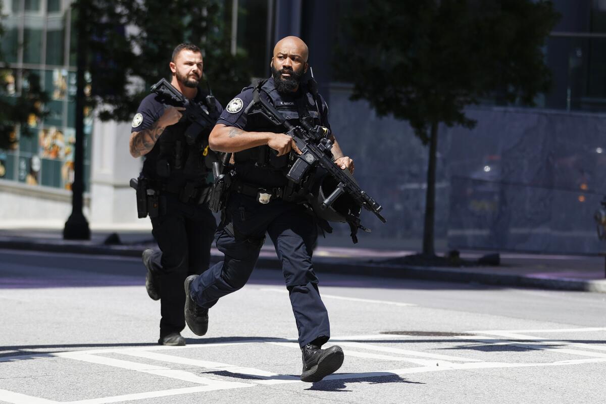 Two men in dark uniforms run while carrying rifles