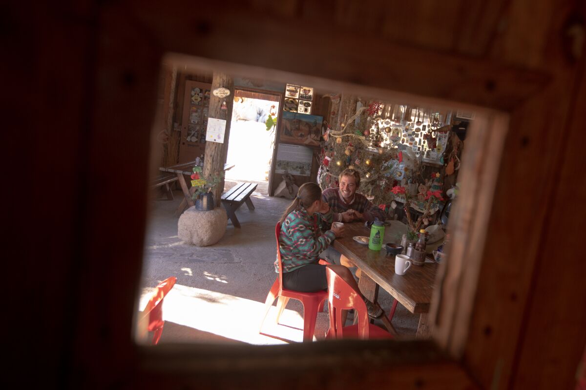 Two people sitting at a table, seen through a window in a door.