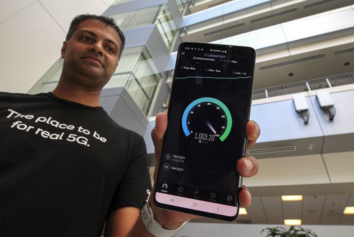 Qualcomm senior staff engineer Vid Adiraju holds a smartphone as it goes through a 5G speed test in this file photo.
