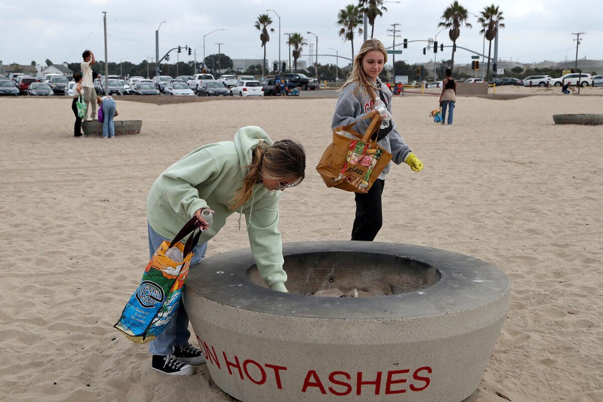 Kayla Pierce, 17, left, and Amber Reuter, 17, right, of Sunny Hills High School, help remove trash during a beach cleanup.