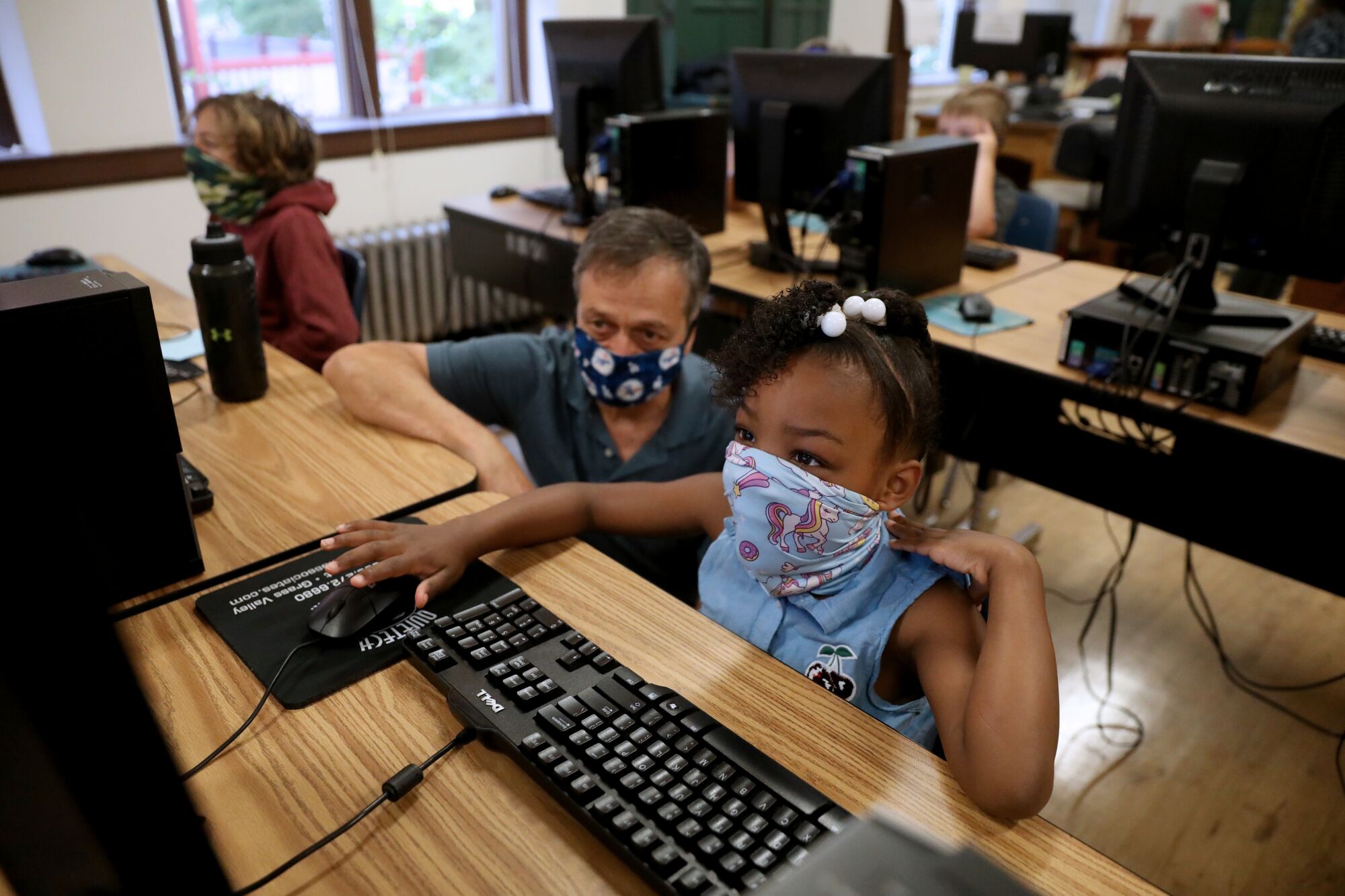 China Arkansas, 8, an incoming third-grader, takes an assessment test while David Pistone, a teacher, looks on.