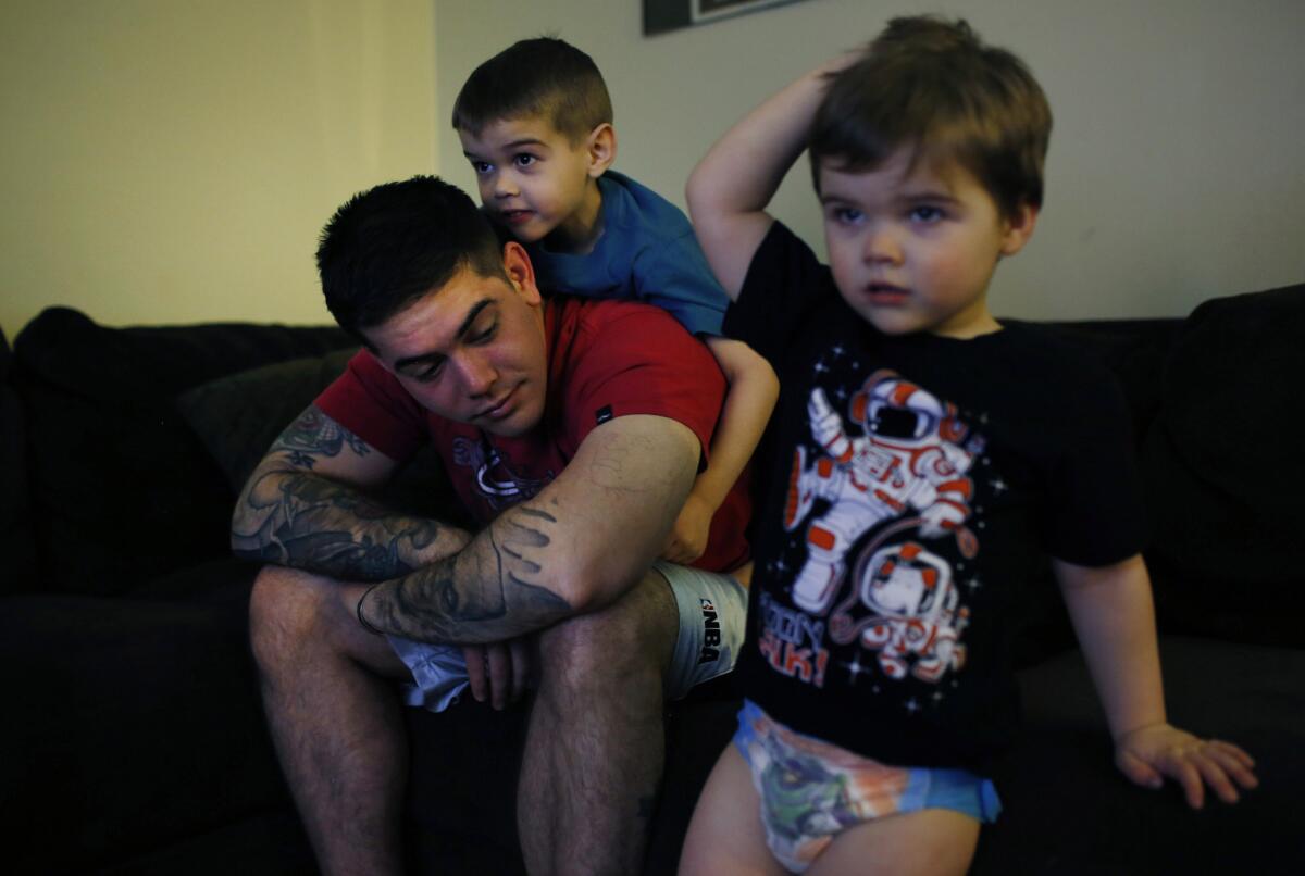 Jayson Morton, a specialist in the army, plays with his two sons, Eli, age 6, left on back, and Silas, age 3, right.