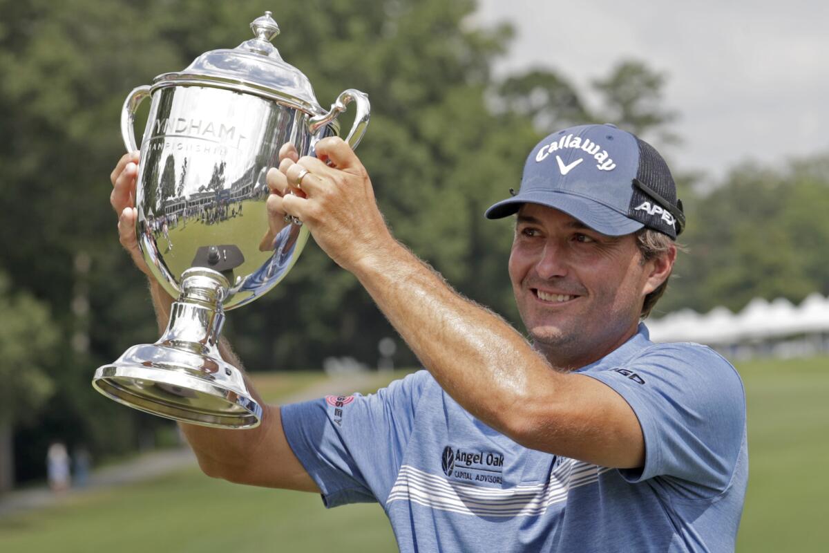 Kevin Kisner hoists the trophy after he sunk a birdie putt on the second playoff hole to win the Wyndham Championship golf tournament at Sedgefield Country Club in Greensboro, N.C., Sunday, Aug. 15, 2021. (AP Photo/Chris Seward)