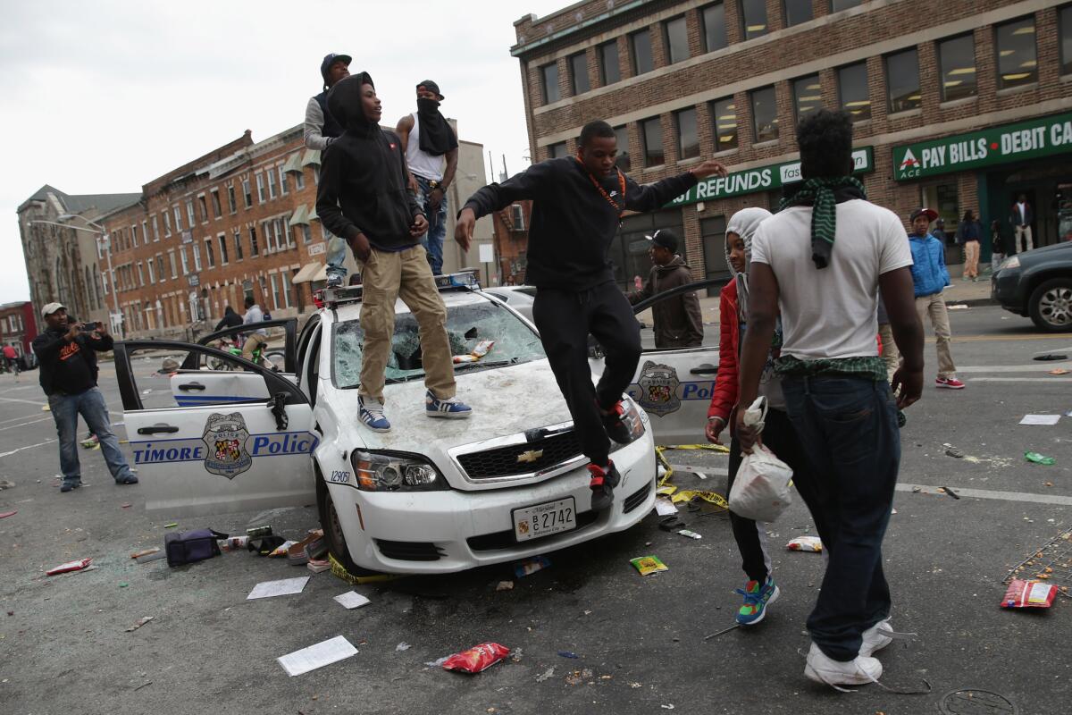 Demonstrators climb on a destroyed Baltimore Police car during violent protests following the funeral of Freddie Gray on April 27, in Baltimore, Maryland.