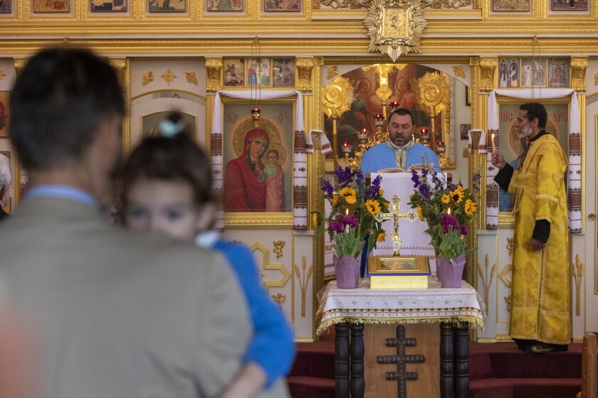 Father Vasile Sauciur, center and subdeacon David De Jesus, right, hold a Mass