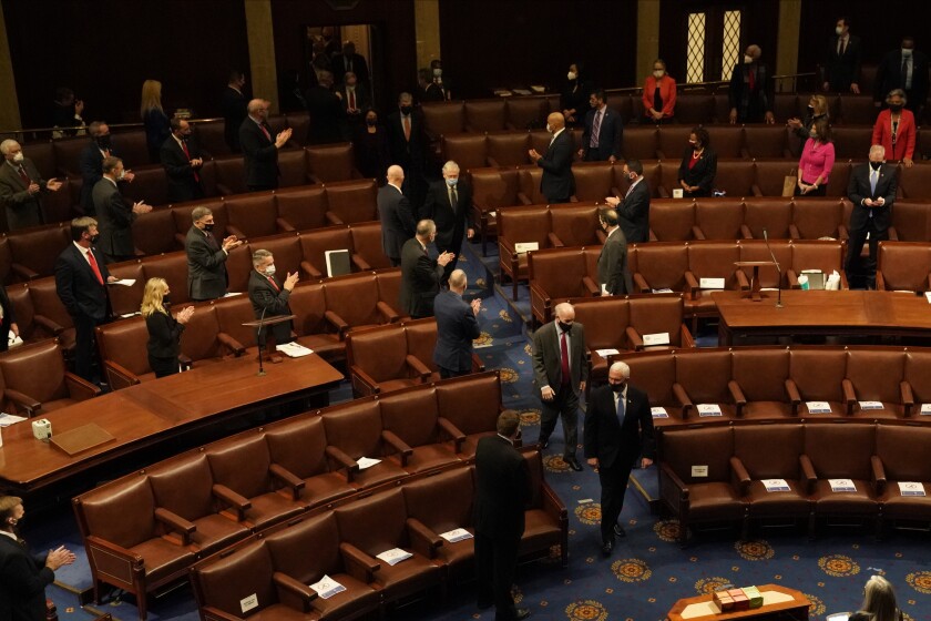 قانونگذاران در حالی ایستاده اند که معاون رئیس جمهور مایک پنس تعدادی از مردم را به داخل سالن هدایت می کند. 