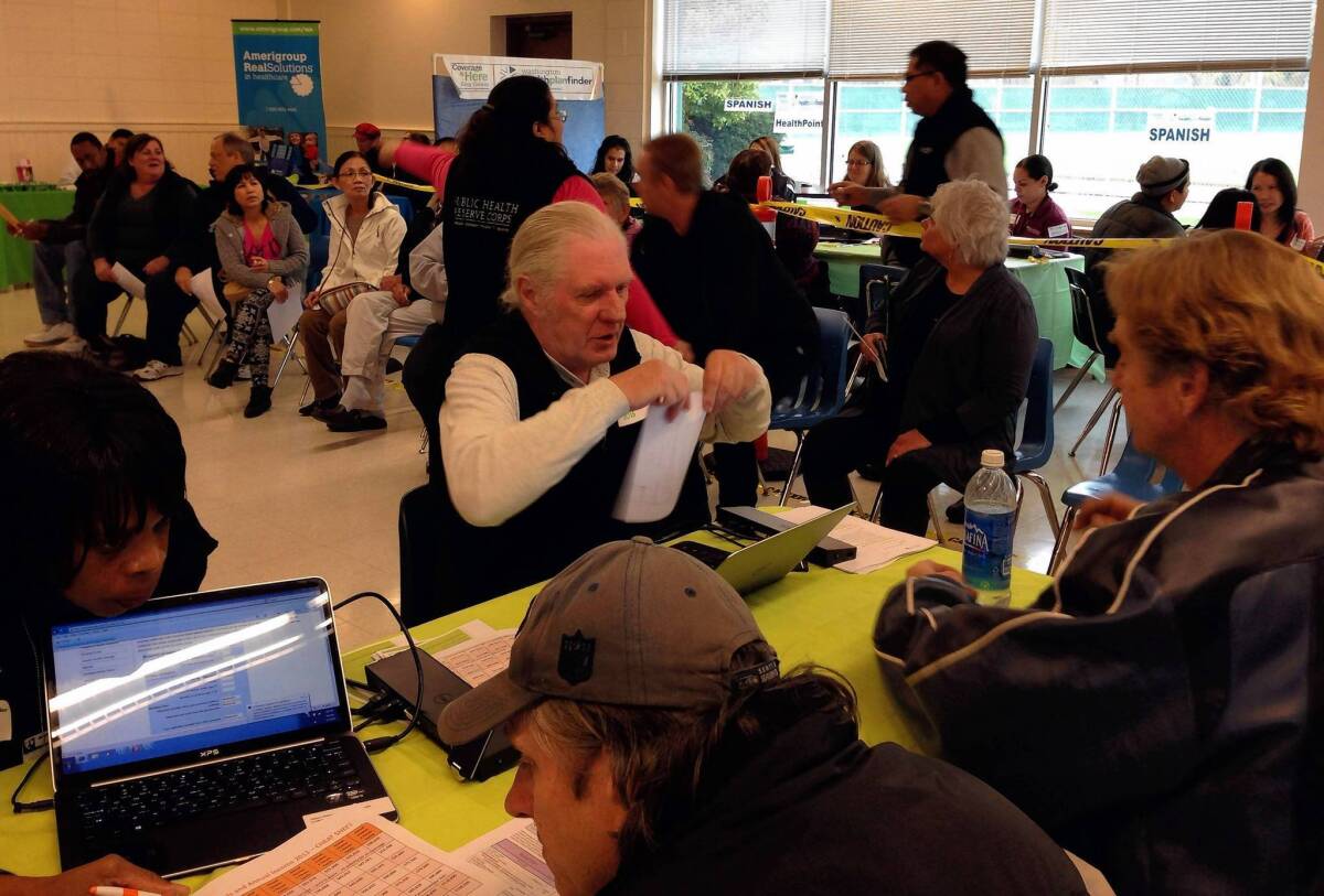 People seeking health insurance compare plans at a Washington Healthplanfinder enrollment event in Kent, Wash.