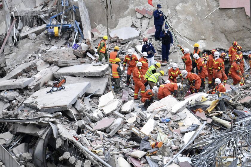 In this photo released by Xinhua News Agency, rescuers search for victims at the site of a hotel collapse in Quanzhou, southeast China's Fujian Province, Sunday, March 8, 2020. Several people were killed and others trapped in the collapse of the Chinese hotel that was being used to isolate people who had arrived from other parts of China hit hard by the coronavirus outbreak, authorities said Sunday. (Lin Shanchuan/Xinhua via AP)
