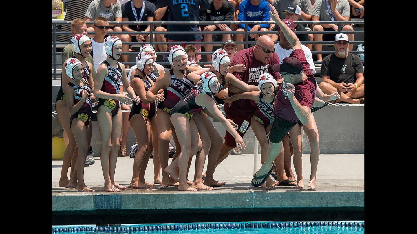 The Laguna Beach 10-and-under girls water polo team pushes head coach Albert Beeler into the water after a win over Huntinton Beach during the USA Water Polo Junior Olympics division title game at Woollett Aquatics Center on Tuesday, July 25.