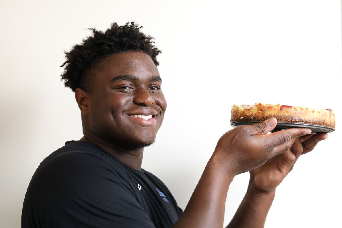 UCLA defensive lineman Otito Ogbonnia holds up a strawberry cheesecake he made in his apartment.