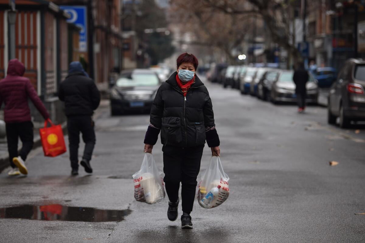 A woman wearing a protective face mask returns from a market in Wuhan, the epicenter of the coronavirus outbreak that has killed at least 170 people in China and infected more than 8,200 worldwide.