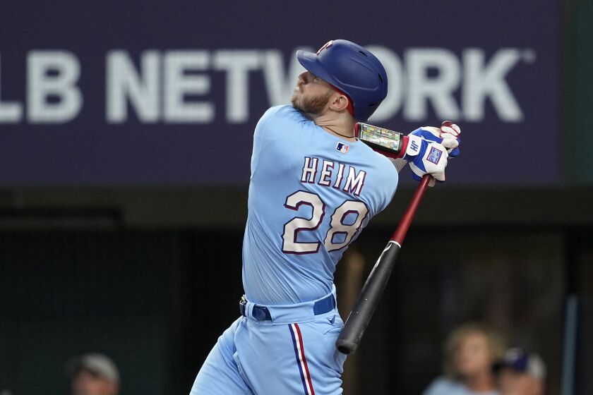Texas Rangers' Jonah Heim follows through on a three-run home run swing in the sixth inning of a baseball game against the Seattle Mariners, Sunday, June 4, 2023, in Arlington, Texas. Josh Jung and Nathaniel Lowe also scored on the shot. (AP Photo/Tony Gutierrez)