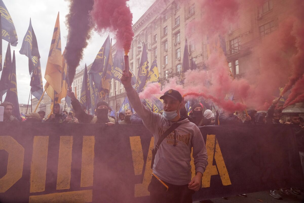 Members of nationalist movements light flares during a rally marking Defender of Ukraine Day, in center Kyiv, Ukraine, Thursday, Oct. 14, 2021. Some 15,000 far-right and nationalist activists march in the Ukrainian capital, chanting "Glory to Ukraine" and waving yellow and blue flags. (AP Photo/Efrem Lukatsky)