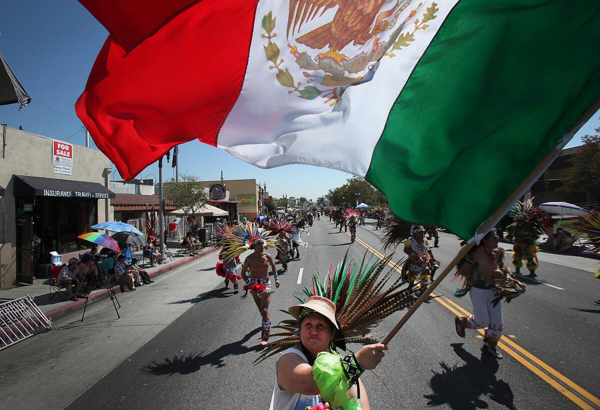 Marchantes y danzantes aztecas caminan por la avenida César Chávez en el desfile anual del Este de Los Ángeles.
