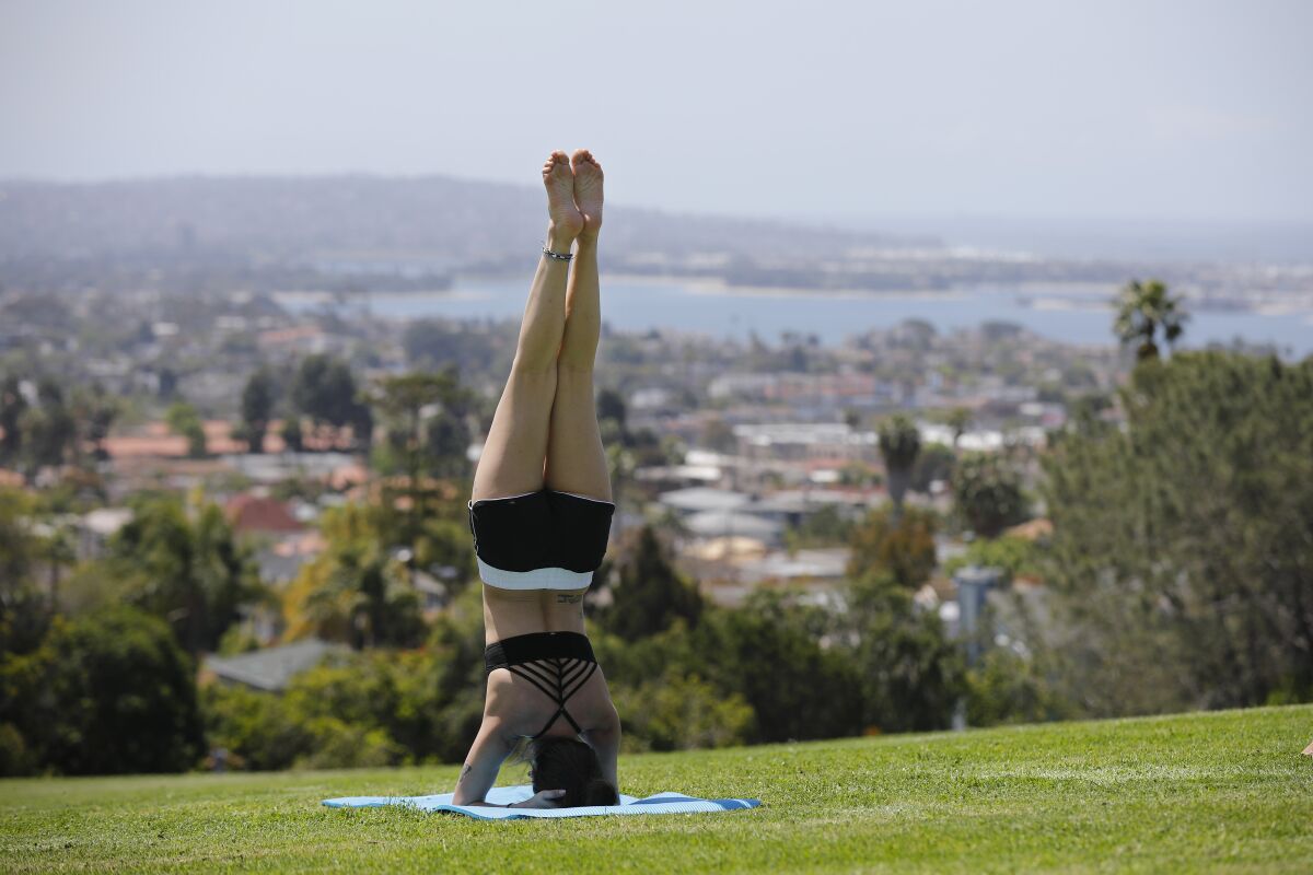 Mandy Delgado does a yoga headstand at Kate Sessions Park in Pacific Beach on April 21, 2020. Most San Diego parks and trails that were closed due to Covid-19 were reopened to the public Tuesday.