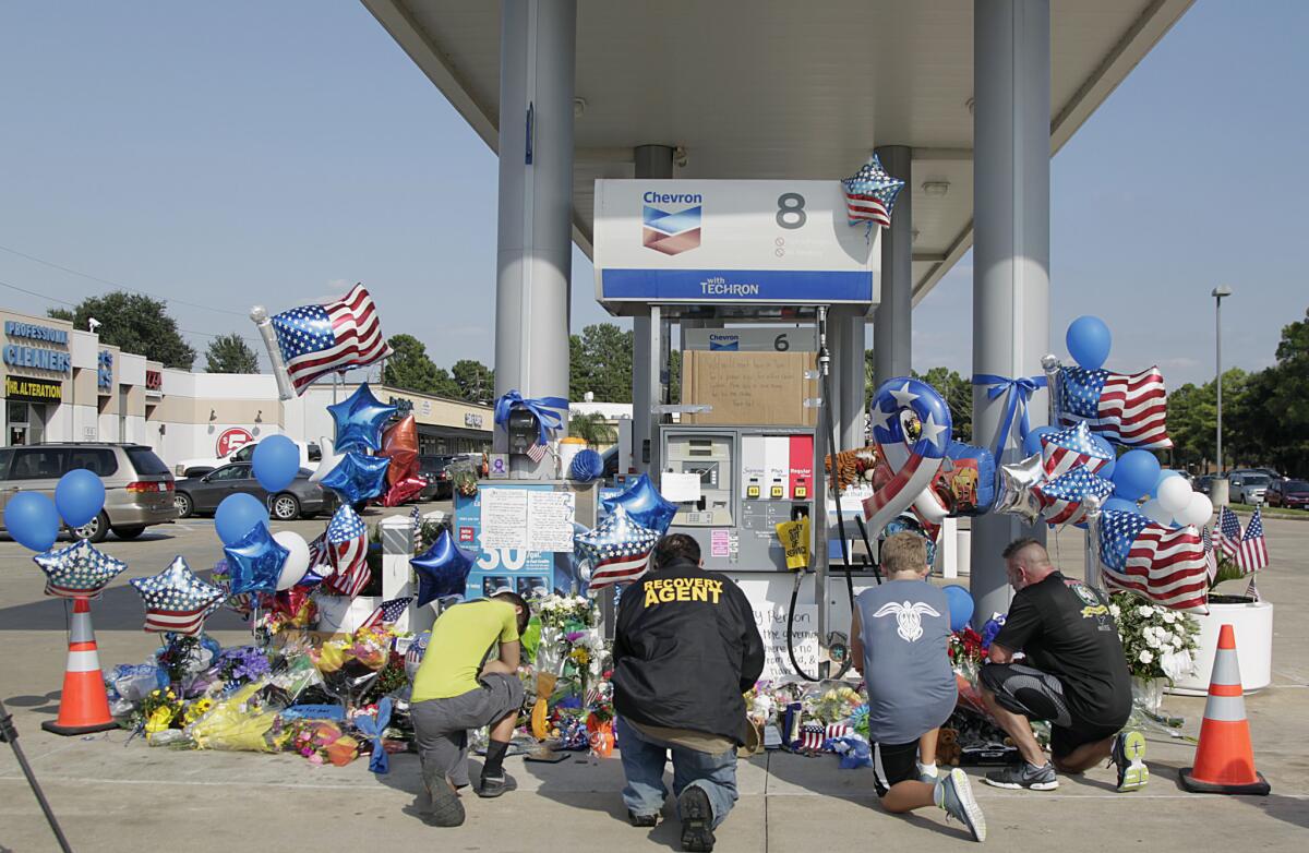 Dolientes oran frente a una gasolinera en Houston donde se erigió un monumento improvisado en memoria del policía Darren Goforth, asesinado mientras repostaba gasolina en su auto patrulla. (James Nielsen/Houston Chronicle vía AP)