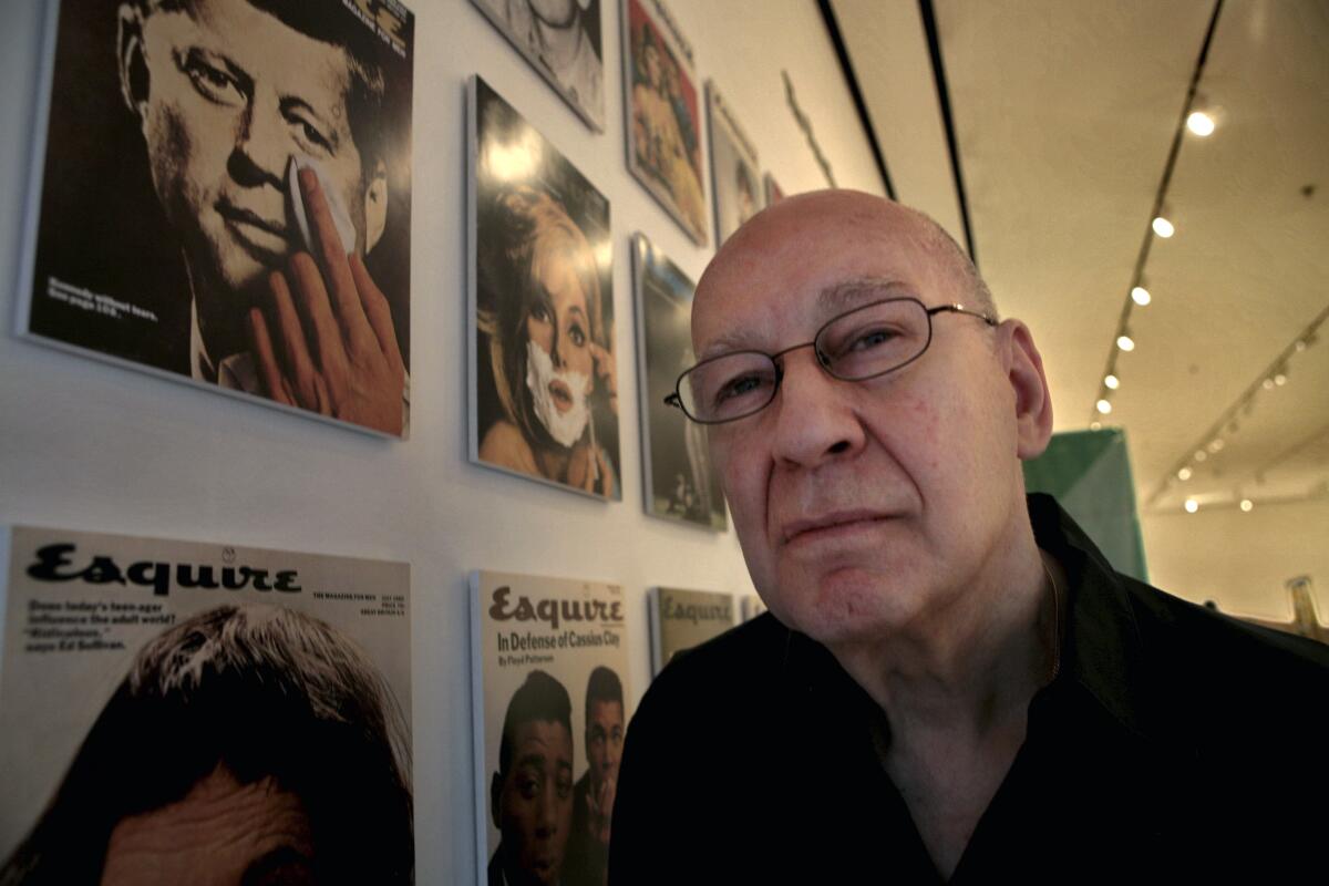 A man posing beside a display of magazine covers.