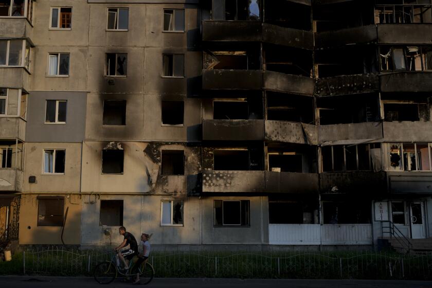 A man rides a bicycle in front of a building destroyed by attacks in Borodyanka, on the outskirts of Kyiv, Ukraine, Sunday, June 12, 2022. (AP Photo/Natacha Pisarenko)