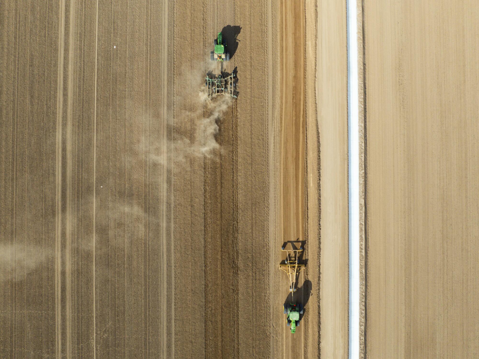 Farm vehicles work an alfalfa field owned by the company Fondomonte, in Vicksburg, Ariz.