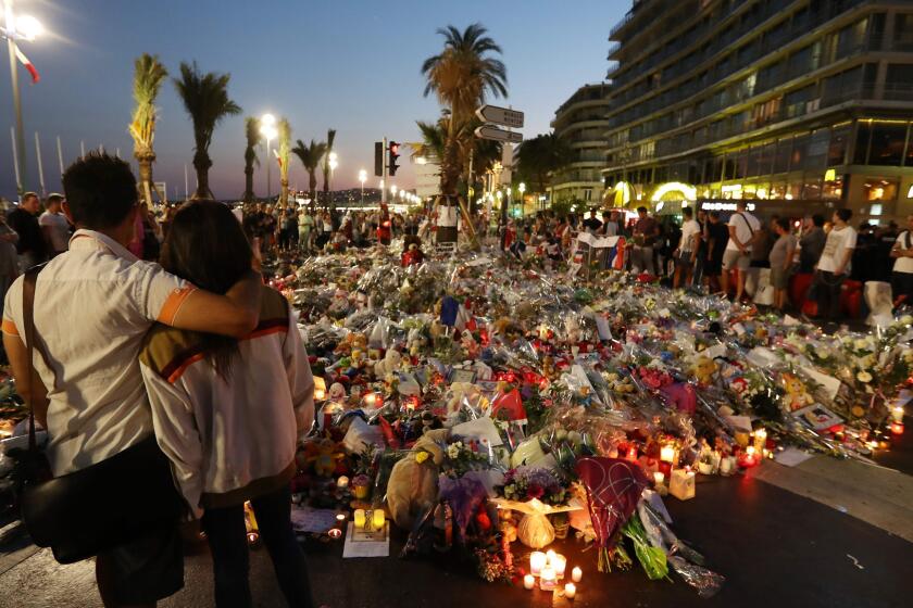 Mourners stand along the promenade in Nice, France, where a makeshift memorial grew after an attacker drove a truck through a Bastille Day crowd.