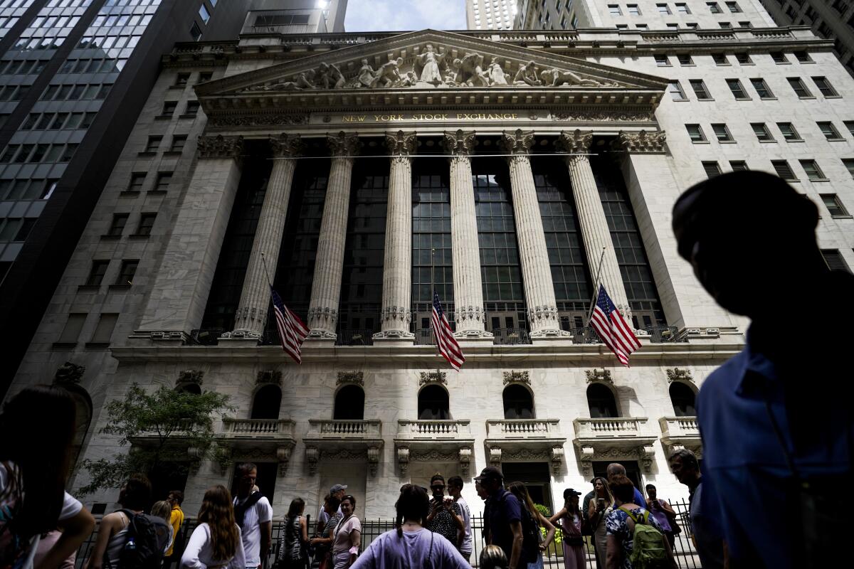 Pedestrians walk past the New York Stock Exchange 