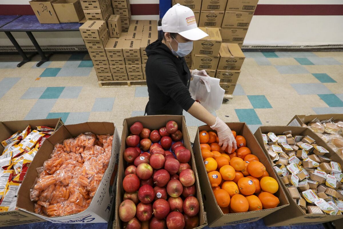 A cafeteria worker amid bins of food