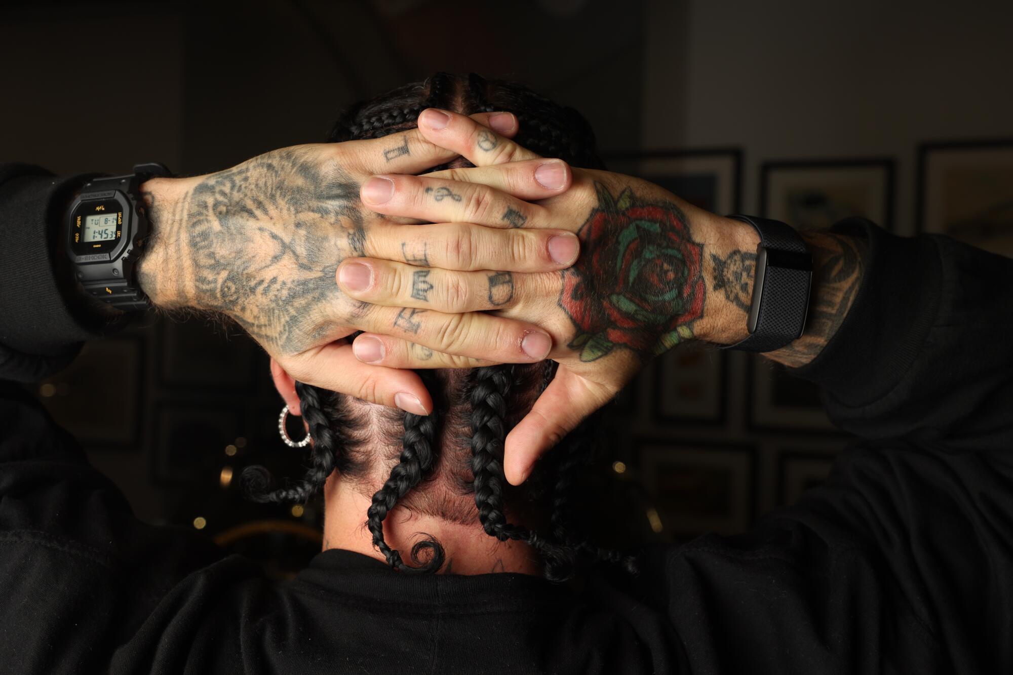 J Balvin shows off his hand tattoos and braids behind his head.