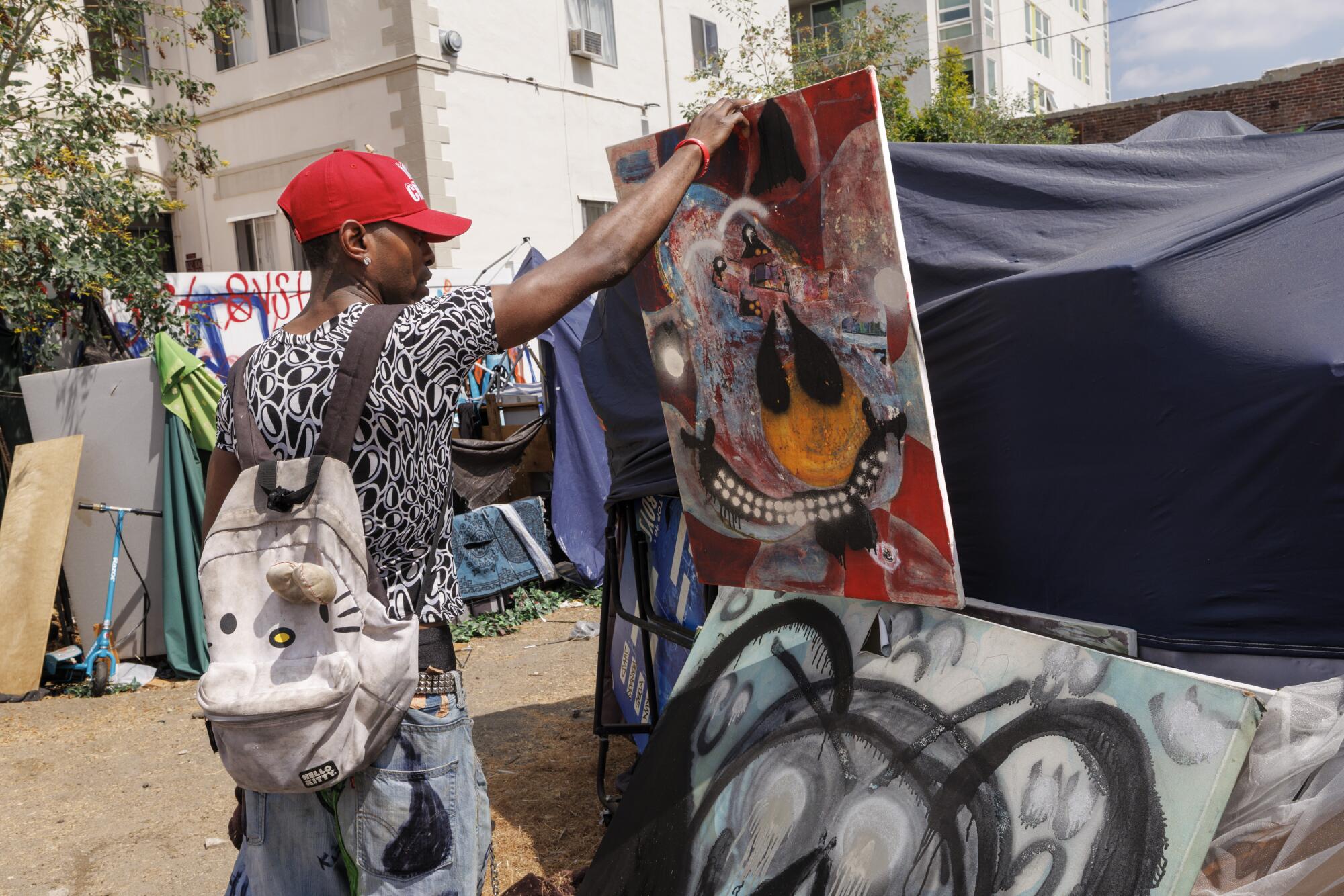 Tahj Banks looks through his art pieces that he produced at a homeless encampment in Koreatown.